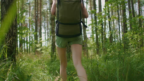 Las-Piernas-De-Una-Mujer-Viajera-Caminando-Por-Un-Camino-Forestal-Con-Un-Mapa-En-El-Bosque-De-Pinos
